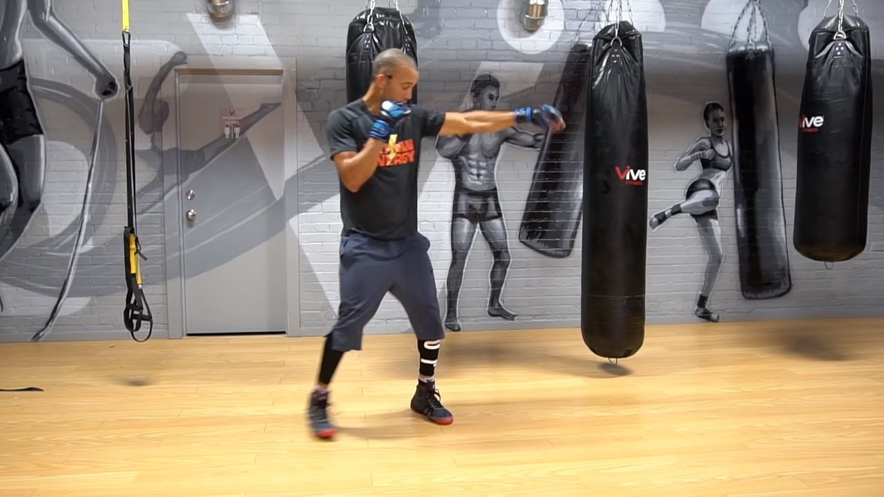 Man practicing boxing punches with heavy bag in a gym
